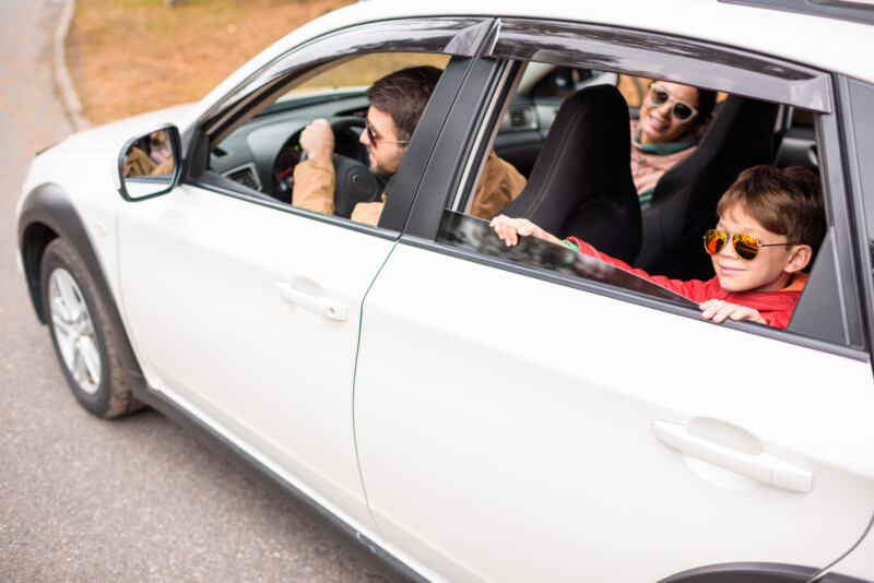 Happy friendly family travelling by car on rural road