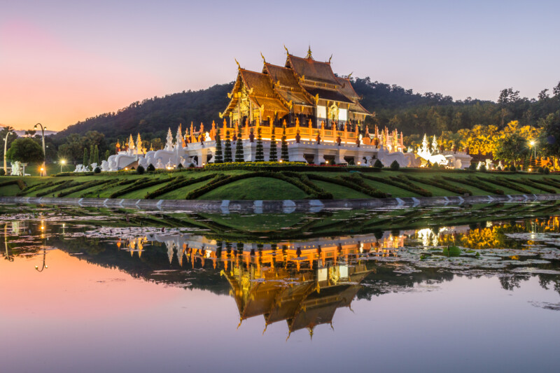 Illuminated Royal Pavilion and its reflection in pond at Royal Flora Ratchaphruek  park. Colorful sky in the evening. Chiang Mai, Thailand